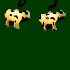 Cow-shaped string lights on green background